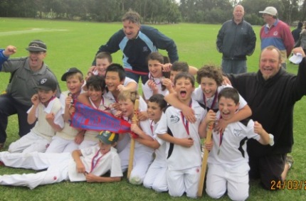 The Under 12 team with their 2011/12 flag and medals. Coach Paul Baks (right) is joined by assistant coaches Michael Cumbo (left) and Bill Blair, while Moonee Valley legends Warwick Nolan and Tony Hicks stand in the background.